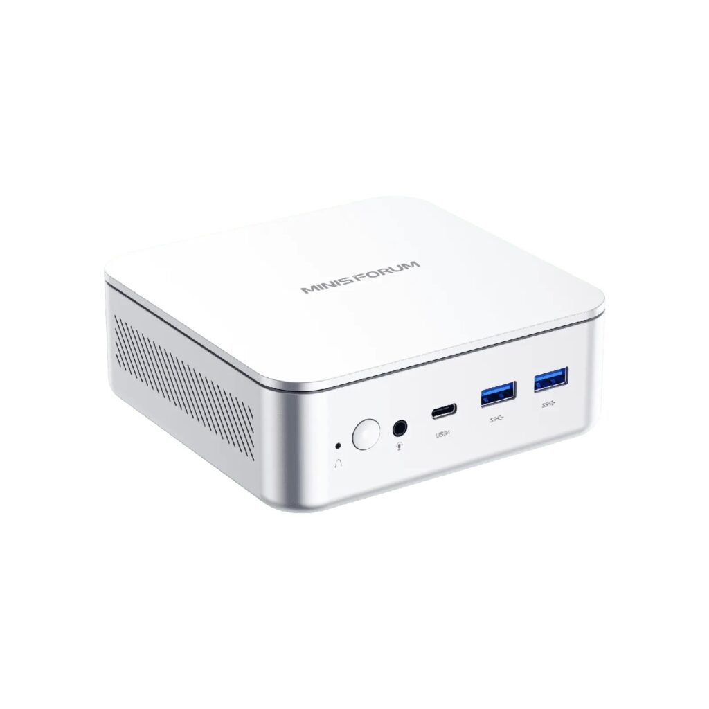 Small unbranded black mini PC on a home office desk beside a monitor and keyboard